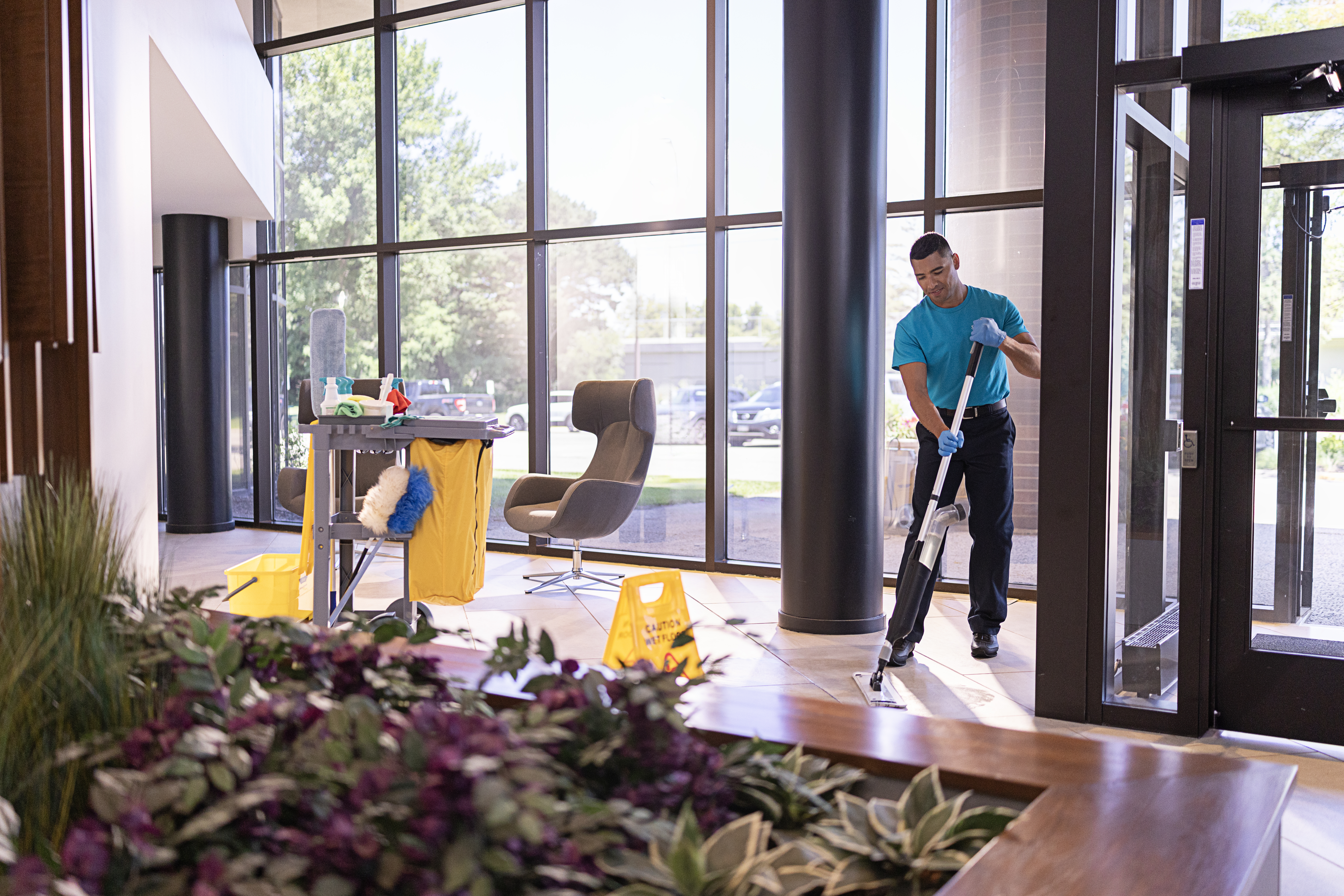 A cleaning technician wiping down a conference room table in a modern office.
