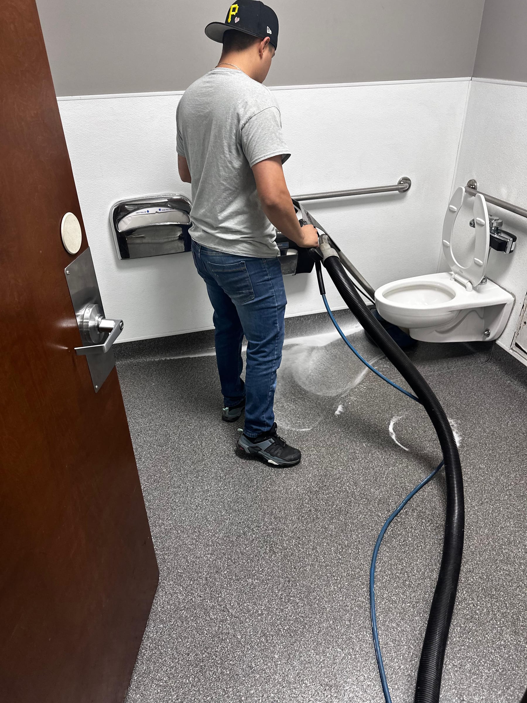 A commercial restroom, tiled and fully restocked, with touch-free dispensers and dry counters.